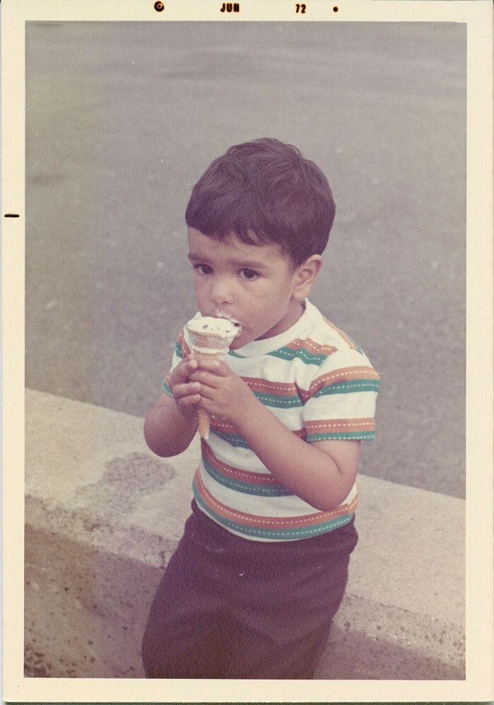 Paul Nasrani as a child eating an ice cream cone outdoors.